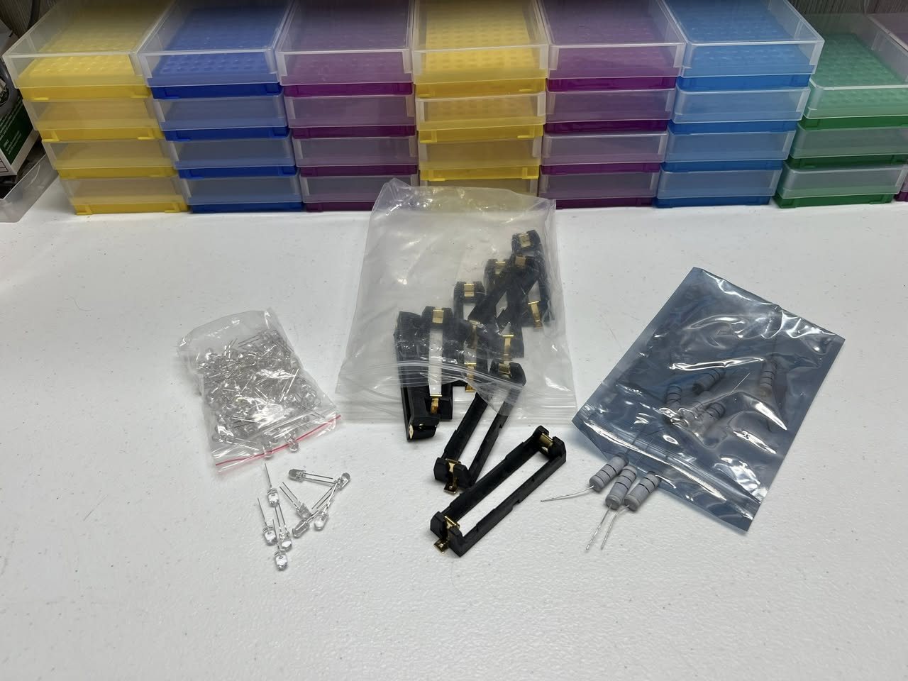 LEDs, 18650 battery clips and resistors laid out on a white table
